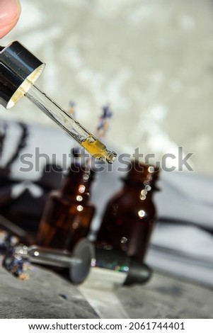 Lavender flowers and aromatic oils on a gray background with shadows Various Facial Massage Oils For Spa Treatments Cosmetic glass bottles with serum Close-Up Of A Dropper With Bottles selective focus