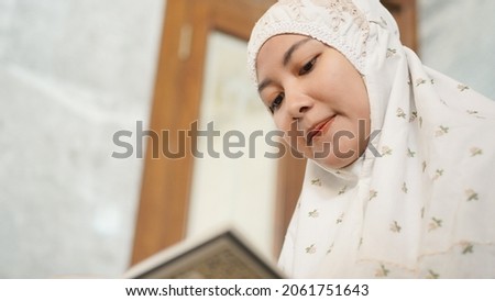 Asian Muslim woman reading the Quran in the mosque