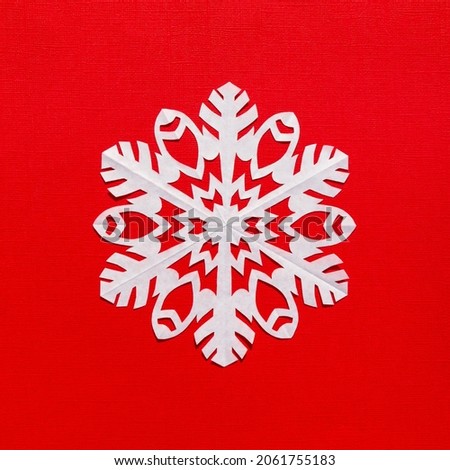 White paper snowflake on a red background, handmade new year decoration