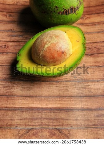 Half of avocado on wooden textured background. it's very juicy fruit and tasty that originally fruit from Indonesia. High quality stock photo of fruit.