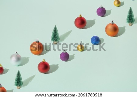 Arranged green New Year and Christmas tree with silver, yellow gold, blue, red, purple and orange bauble,  on a mint pastel background. Pattern. Copy space.