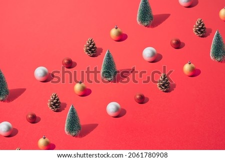 Arranged New Year and Christmas tree with yellow gold, silver, red  bauble and brown pinecone on a red pastel background. Pattern. Copy space.