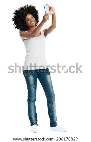 Studio shot of attractive african woman with afro taking a picture of herself with her camera phone