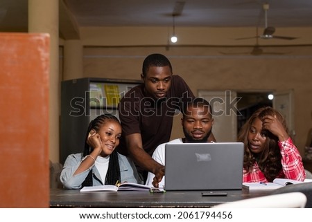 a group of black students studying together, using a laptop to discuss their work