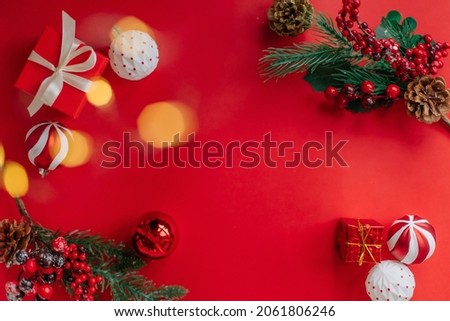 Christmas 2022. Fir branches, a gift. toys and balls with new year decorations on red background with bokeh. Holiday greeting card design. free copy space, place for text