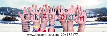 Children Hands Building Colorful English Word Freedom. Snowy Winter Background With Snowflakes