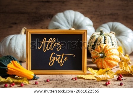 Autumn Pumpkin Decoration With German Text Alles Gute Means Best Wishes. Wooden Background with Corlorful Rustic Fall Decor Like Leaf And Golden Picture Frame