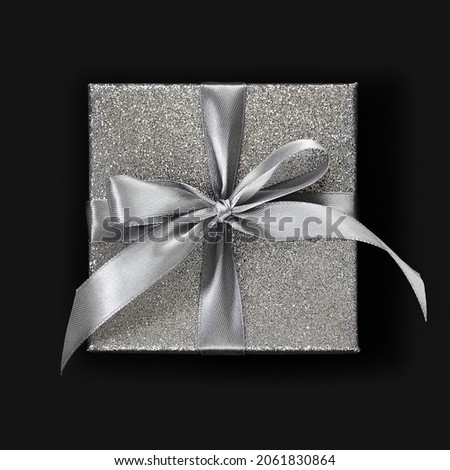 gift silver glittering box with ribbon bow, isolated on black background, top view, useful for merry christmas, black friday or cyber Monday shopping concept