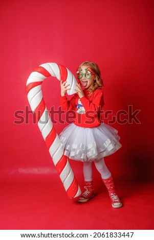 little  girl on a red the background with a large caramel 