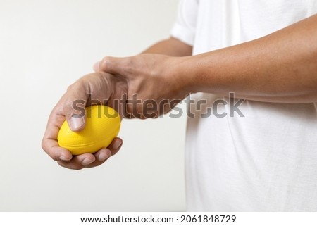 Hands of asian male holding a stress ball,man patient doing hand and wrist exercise,training with rubber ball,squeezing for muscle strength,treatment of hand finger weakness,physical therapy,recovery