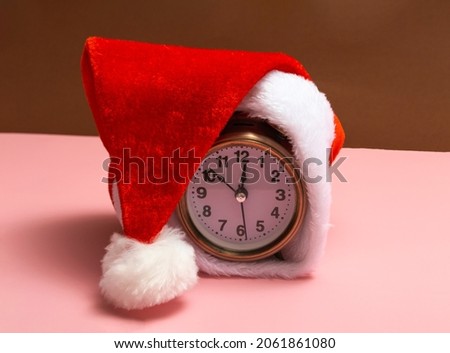 Alarm clock with santa hat on a colored background. New year shopping concept. Close up with copy space. 