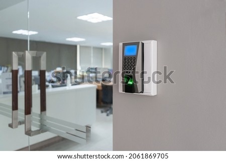 Finger print scan access control system machine on wall near entrance door office.