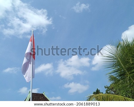 red and white flag tied to a flagpole, against a blue sky background. indonesian flag.