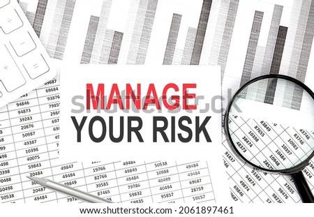 MANAGE YOUR RISK text on paper with calculator,magnifier ,pen on the graph background