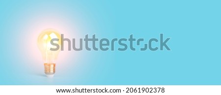 Knowledge and idea concept. Light bulb with light on a blank blue banner background. Brain, wisdom, knowledge and energy conservation is a creative idea. Royalty-Free Stock Photo #2061902378