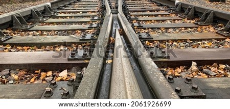 CloseUp of Two railways merge in to one railway.Close up of Two railroads merge into one railroad. Autumn leaves on railway (railroad). Close up of railroad (railway). Royalty-Free Stock Photo #2061926699