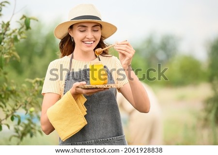 Female beekeeper with honey at apiary