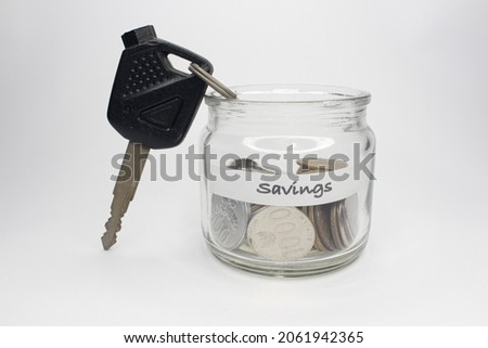Saving coins in the jar and the key to the concept of consumerism in the future, isolated on a white background.