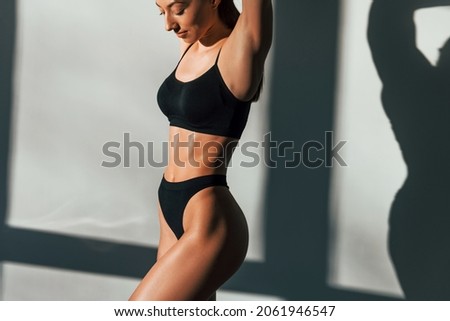 In black underwear. Young caucasian woman with slim body shape is indoors at daytime. Royalty-Free Stock Photo #2061946547