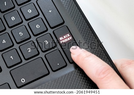 Keyboard corner of black laptop with female finger clicking on Black Friday button. Shopping concept
