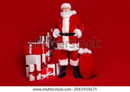 Photo of cheerful handsome retired man wear santa claus costume spectacles smiling preparing presents isolated red color background