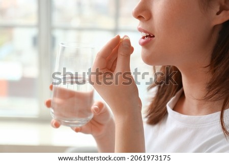 Young woman taking pills at home Royalty-Free Stock Photo #2061973175