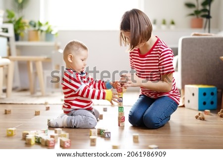 Sister and brother playing with toys together on the floor indoors. Royalty-Free Stock Photo #2061986909