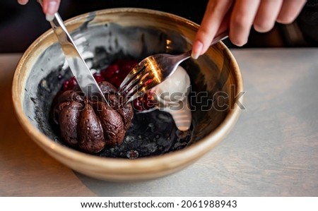 Young woman hand eating chocolate fondant dessert using knife and fork fom bowl