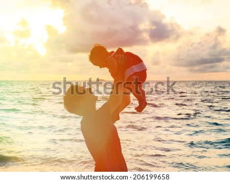 Father and little daughter silhouettes on beach at sunset