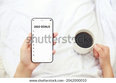 women holding 2022 goals list on mobile phone and cup of coffee, setting New Year goals and resolutions Royalty-Free Stock Photo #2062000010