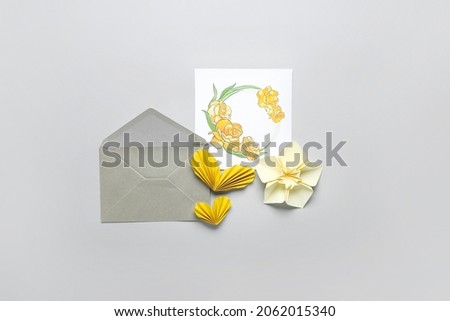 Origami narcissus flower, envelope and greeting card on light background