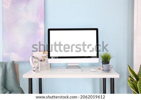 Stylish workplace with modern computer on table near color wall