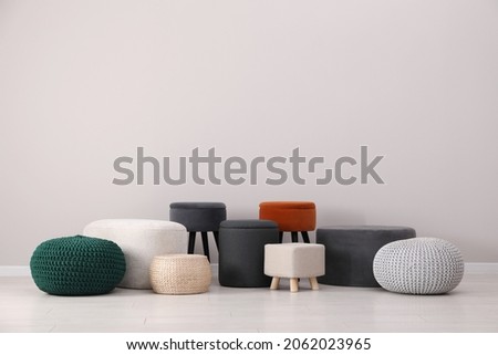 Different stylish poufs and ottomans near light grey wall Royalty-Free Stock Photo #2062023965