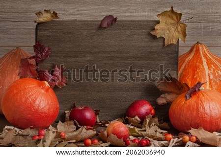 autumn still life harvest with pumpkins, apples and autumn leaves with text board copy space