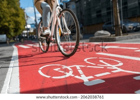 traffic, city transport and people concept - woman cycling along red bike lane with signs of bicycles on street Royalty-Free Stock Photo #2062038761