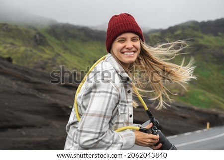 Woman with camera laughing out loud while taking photos in the mountains and hills