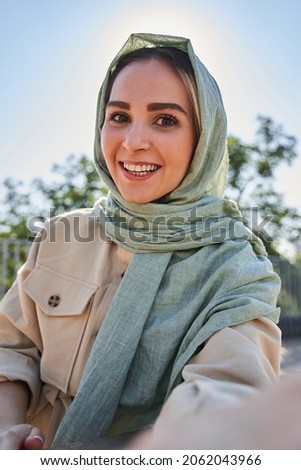 Woman in abaya recording video at the selfie camera while spending time at the street Royalty-Free Stock Photo #2062043966