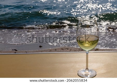 A glass of white wine. Wine against the backdrop of the sea coast and a sunny summer beach. Wine tasting and relaxation at the resort