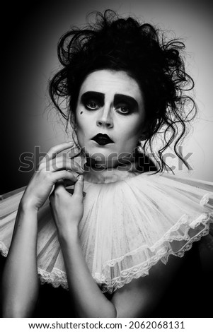 Black and white portrait of attractive woman in artistic costume for party, with creepy makeup isolated over black background. Concept of party, costume, creativity, Halloween, ad