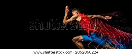 Developing strength. Young male athlete, professional runner in motion isolated over black background. Stroboscope effect. Concept of sport, action, energy, health, movement. Copy space for ad Royalty-Free Stock Photo #2062068224