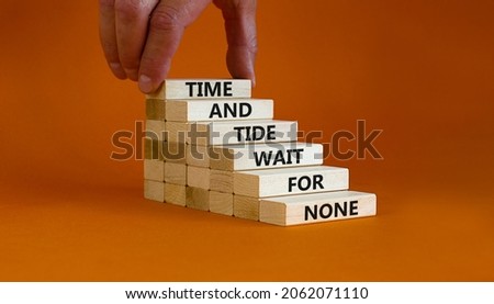 Time to action symbol. Wooden blocks with words time and tide wait for none. Beautiful orange background. Businessman hand. Business and time to action concept. Copy space.