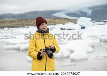 Woman in yellow raincoat looking away while taking photography at her camera