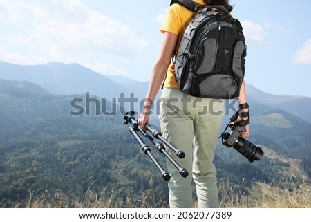 Professional photographer with modern camera and tripod in mountains, closeup