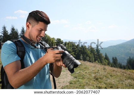 Professional photographer with modern camera in mountains. Space for text