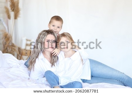 studio shooting of a young mother with her son and daughter on a light background