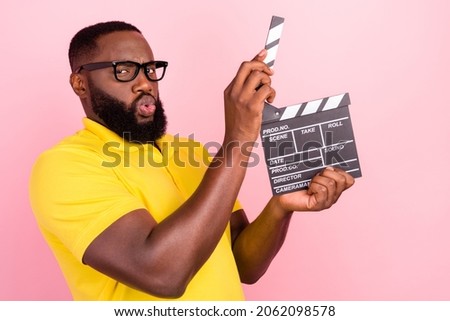 Photo of afro american brown haired man wear glasses yellow t-shirt hold clapper glasses isolated on pink color background