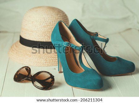 Retro style image of female fashion: straw hat, sun glasses and turquoise shoes over white wooden background. Selective focus, shallow DoF, vintage filters