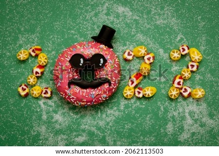 Numbers 2022 from doughnut and candies. Conceptual photography. Diet. Banner. Business. New Year. Green background.