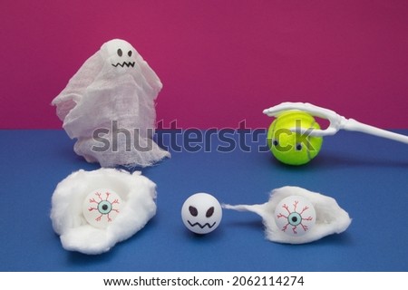 Creepy spirit, a tennis ball with eyes with skeleton hand and in front of them dominant eyes on a green-blue background with a crazy head in the foreground. Halloween scene.