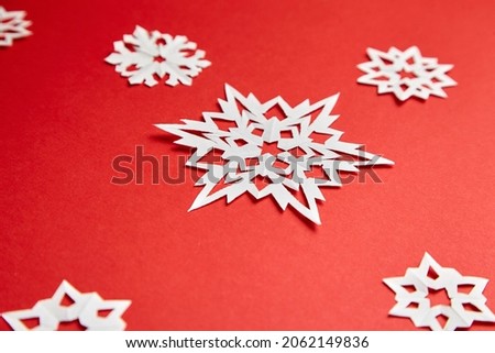 Christmas decoration with white paper snowflakes on red background